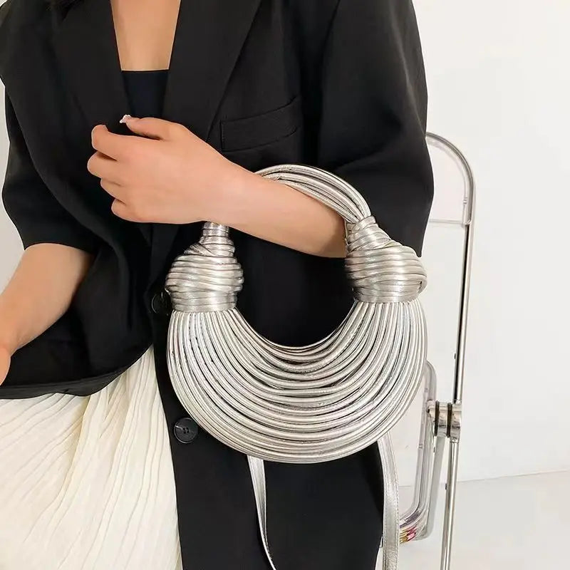 Make a statement with this gold luxury designer brand handwoven noodle bag. With a rope-knotted hobo design and a chic silver evening clutch, this bag is the epitome of high fashion and sophistication. -