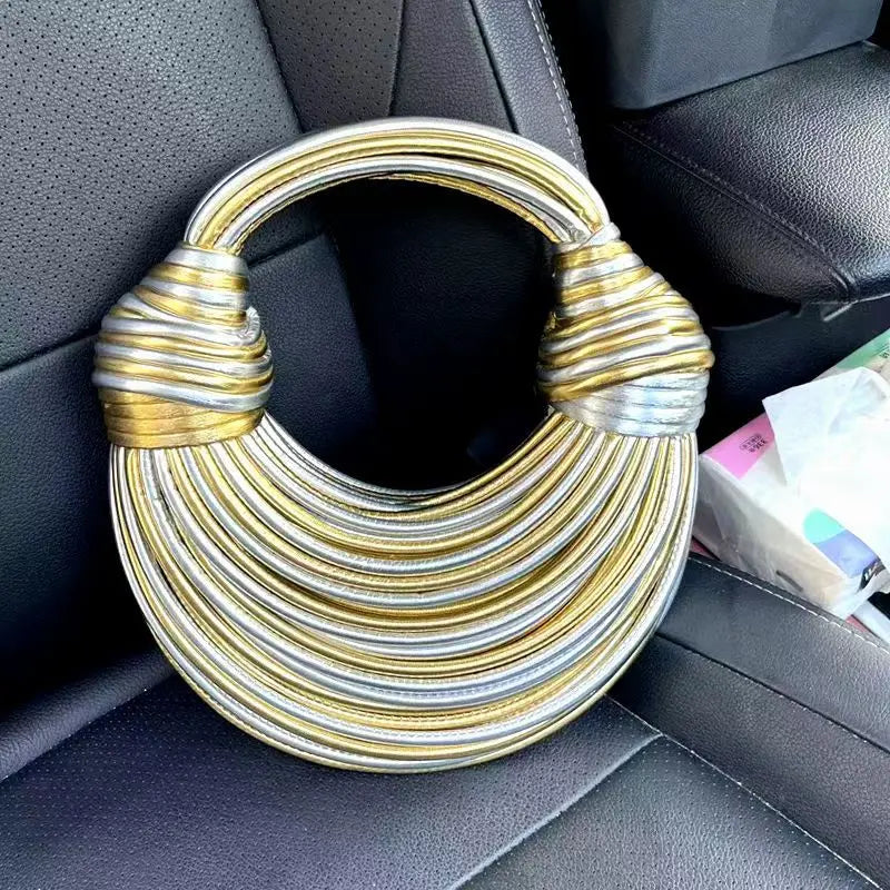 Make a statement with this gold luxury designer brand handwoven noodle bag. With a rope-knotted hobo design and a chic silver evening clutch, this bag is the epitome of high fashion and sophistication. -