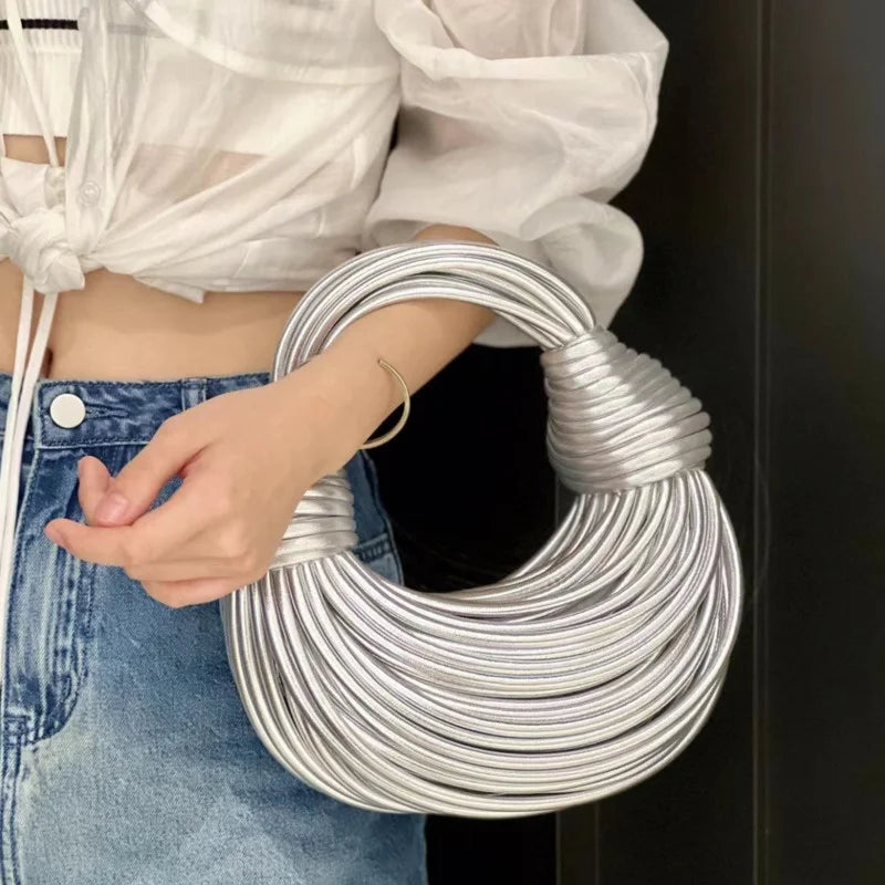 Make a statement with this gold luxury designer brand handwoven noodle bag. With a rope-knotted hobo design and a chic silver evening clutch, this bag is the epitome of high fashion and sophistication. -