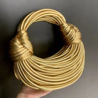 Make a statement with this gold luxury designer brand handwoven noodle bag. With a rope-knotted hobo design and a chic silver evening clutch, this bag is the epitome of high fashion and sophistication. -