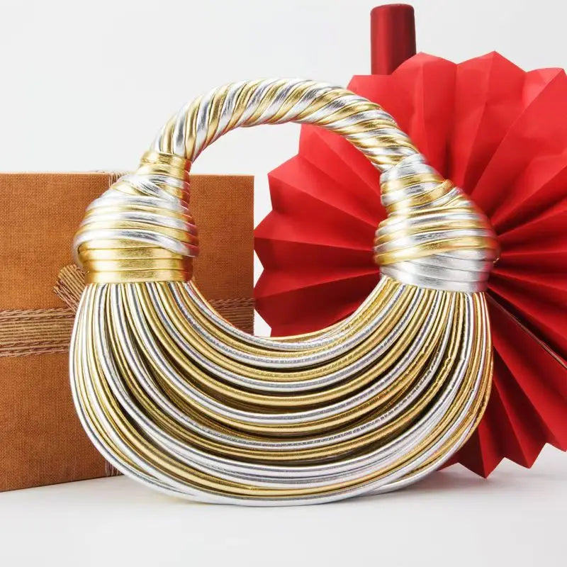 Make a statement with this gold luxury designer brand handwoven noodle bag. With a rope-knotted hobo design and a chic silver evening clutch, this bag is the epitome of high fashion and sophistication. -